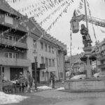 2 Fotos: Hängen der Fasnachtsbändel beim Hexenbrunnen in der Kirchstraße, Fasnacht 1989