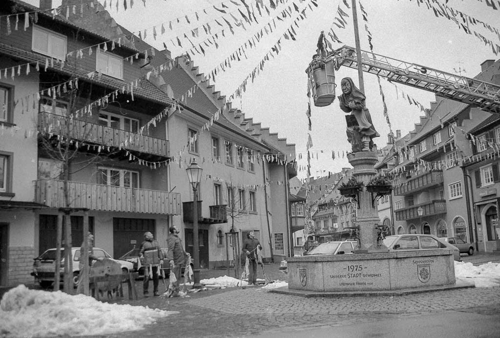 2 Fotos: Hängen der Fasnachtsbändel beim Hexenbrunnen in der Kirchstraße, Fasnacht 1989